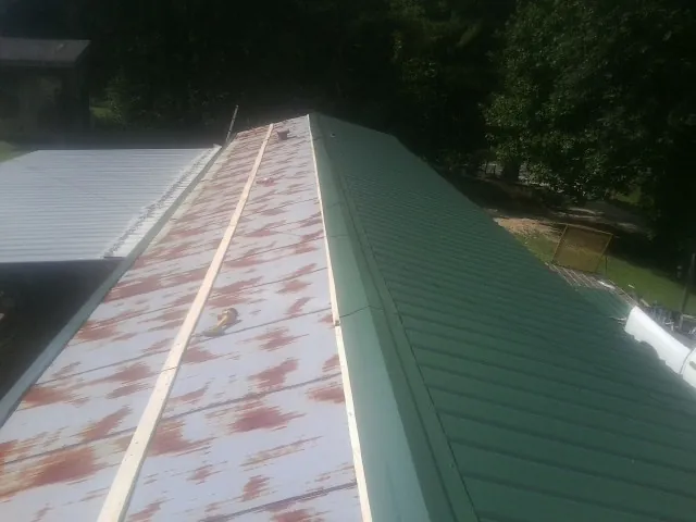 Old rusted panels beside newly installed green metal roofing — Wind Damage Roof Repair by Roofing Brothers in Stanfordville