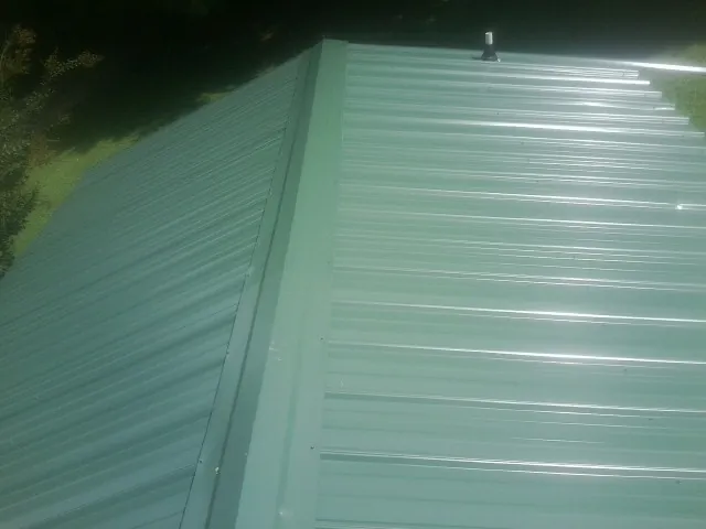 New green metal panels meeting at the ridge of a roof — Flat Roof Repair work by our crew in Stanfordville