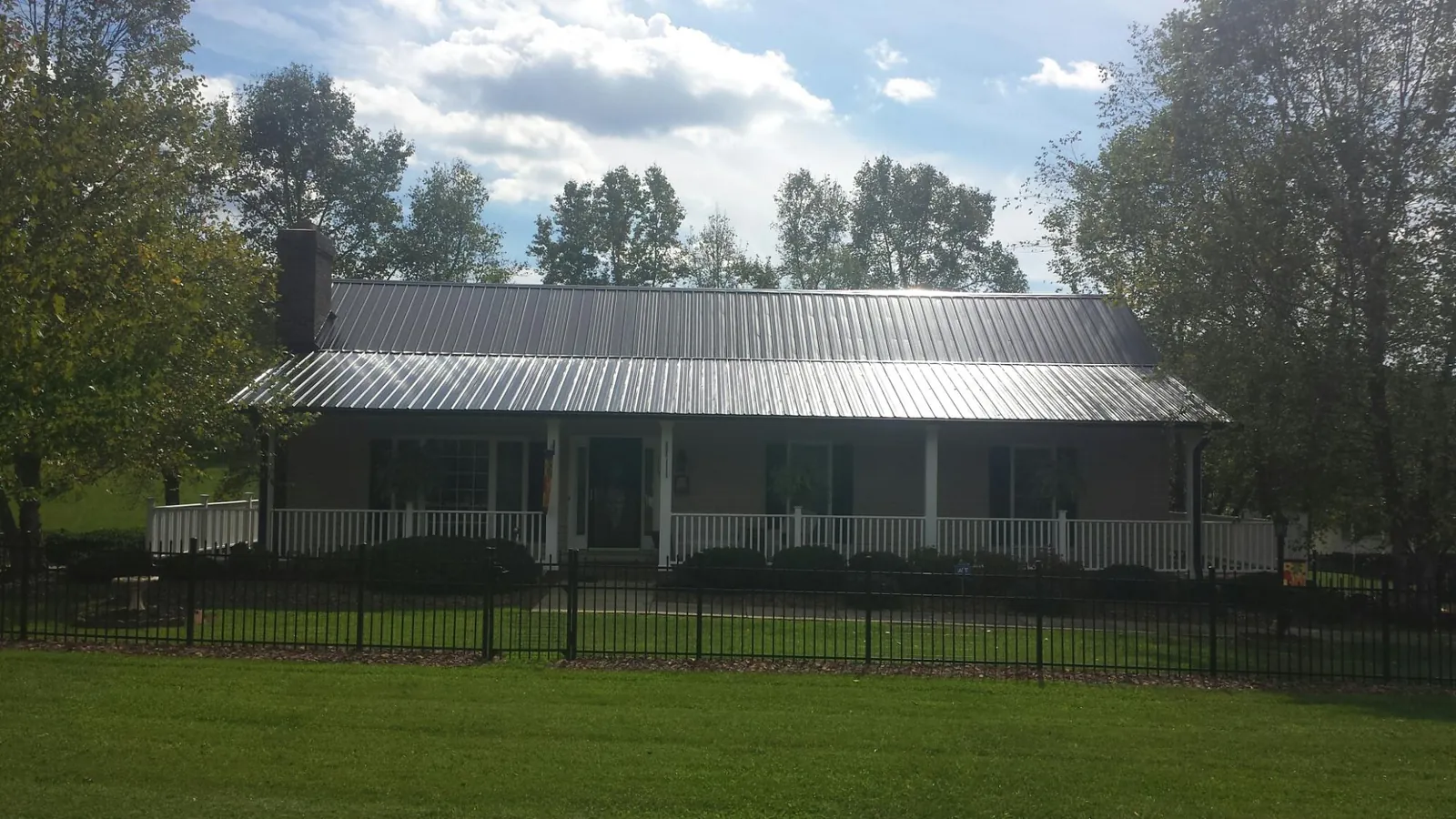 Gray metal roof on a brick ranch with a full width front porch — Gutter Guard Installation work by our crew in Stanfordville