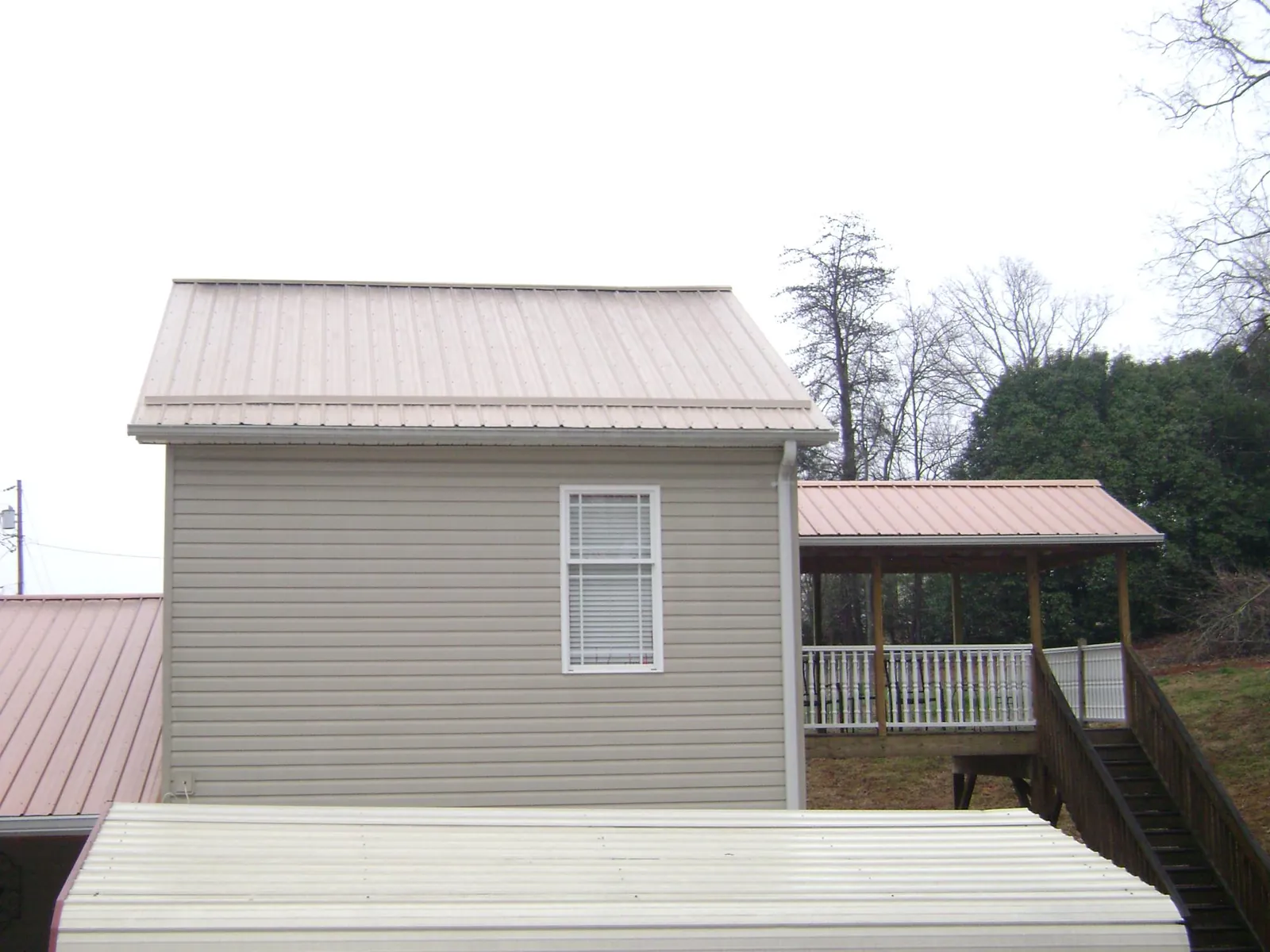 Tan metal roofs on a two story addition and attached porch, from a Roof Replacement job in Stanfordville