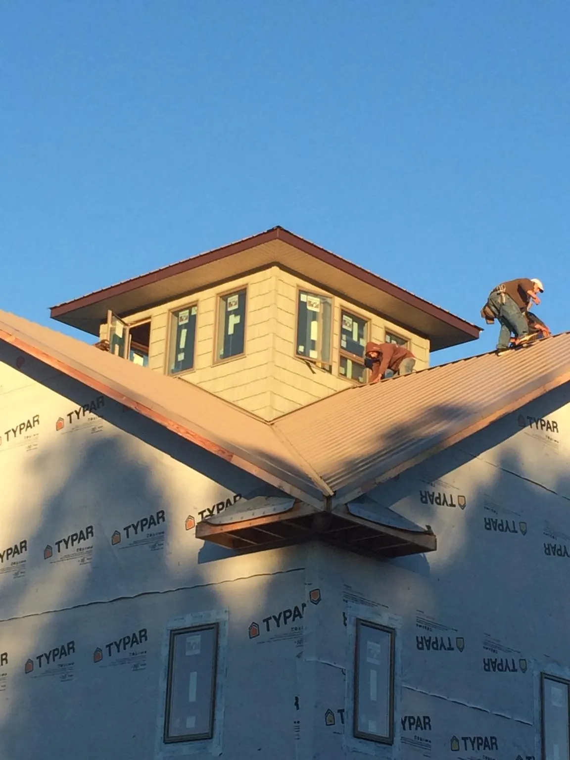 Roofers working around a rooftop cupola on a new metal roof at sunset — Roof Waterproofing in Stanfordville by Roofing Brothers